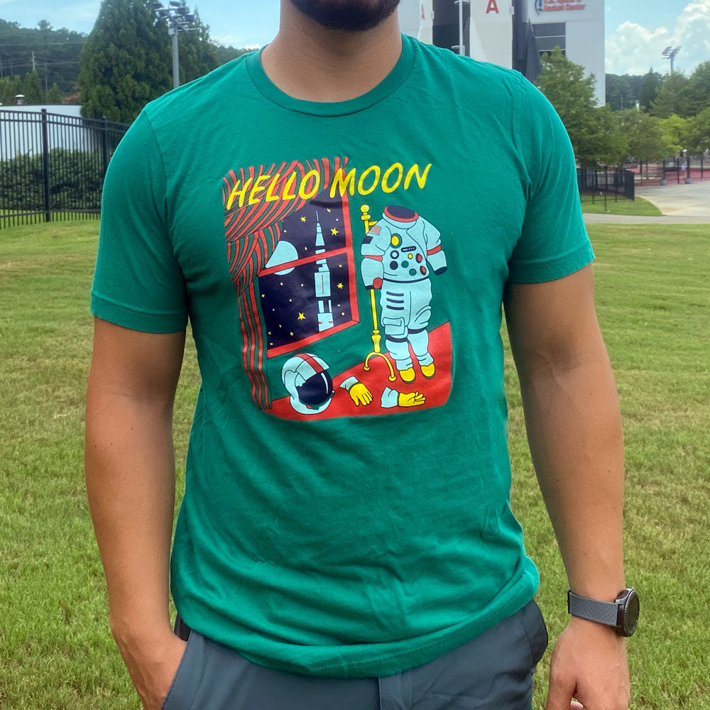 a person wearing a shirt with the text "Hello Moon" with an astronaut suit and rocket. In the "goodnight moon" book style on a green shirt