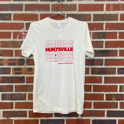 Image of red text "Huntsville Have a Nice Day" on white shirt hanging against brick wall in Lowe Mill