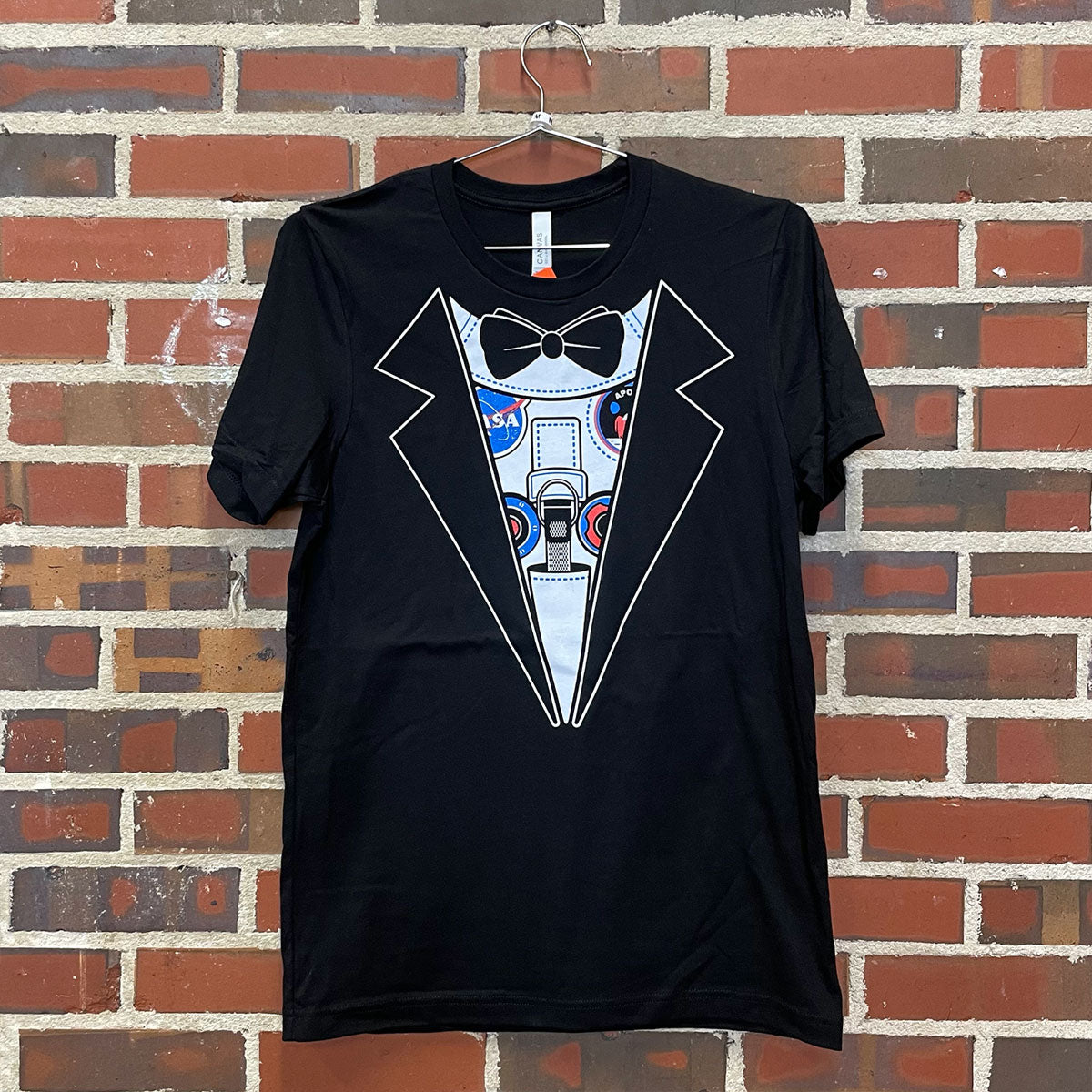 Faux Tuxedo Space suit design on a black t-shirt against a red brick wall