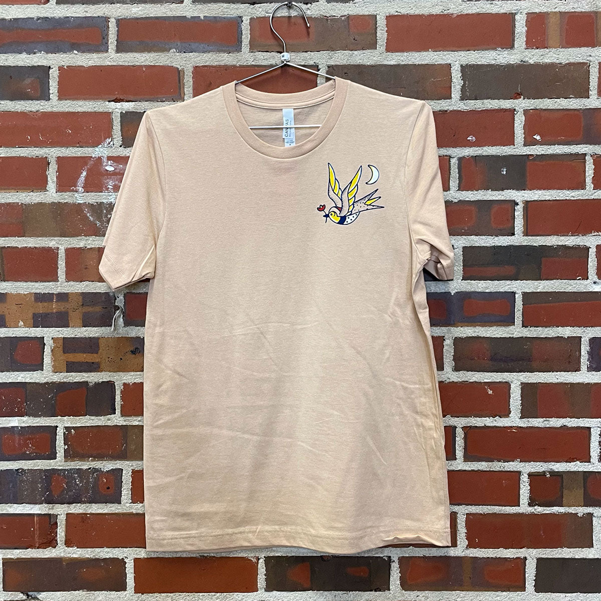 Cream colored shirt of the alabama state bird holding the alabama state flower drawn in american traditional tattoo style