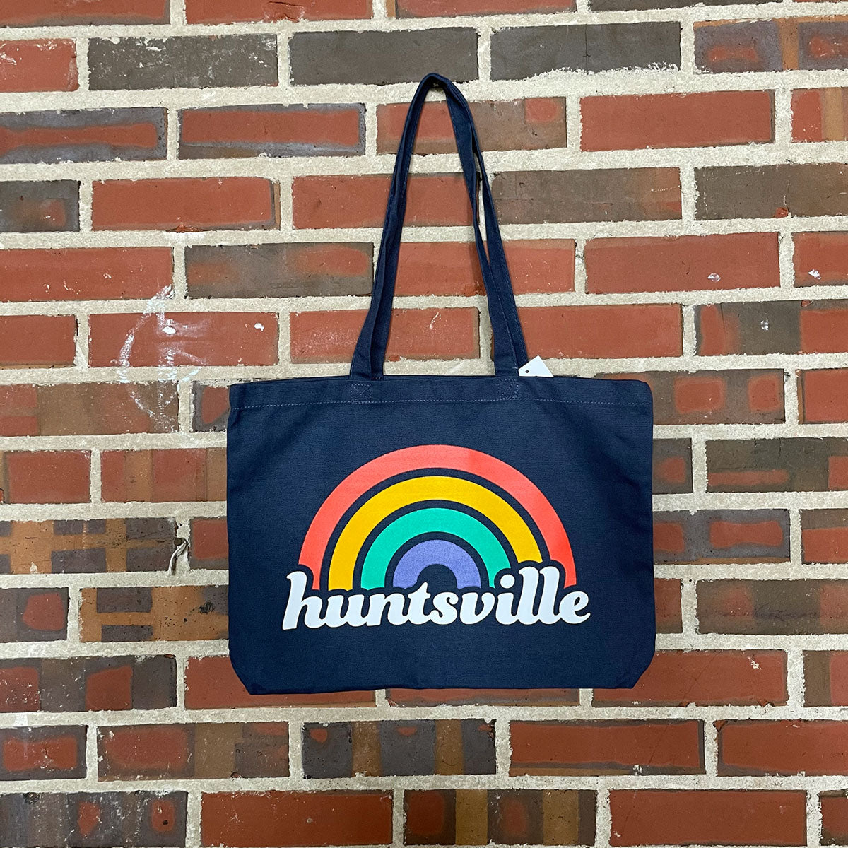 Dark blue tote bag of the text "huntsville" with a rainbow over it